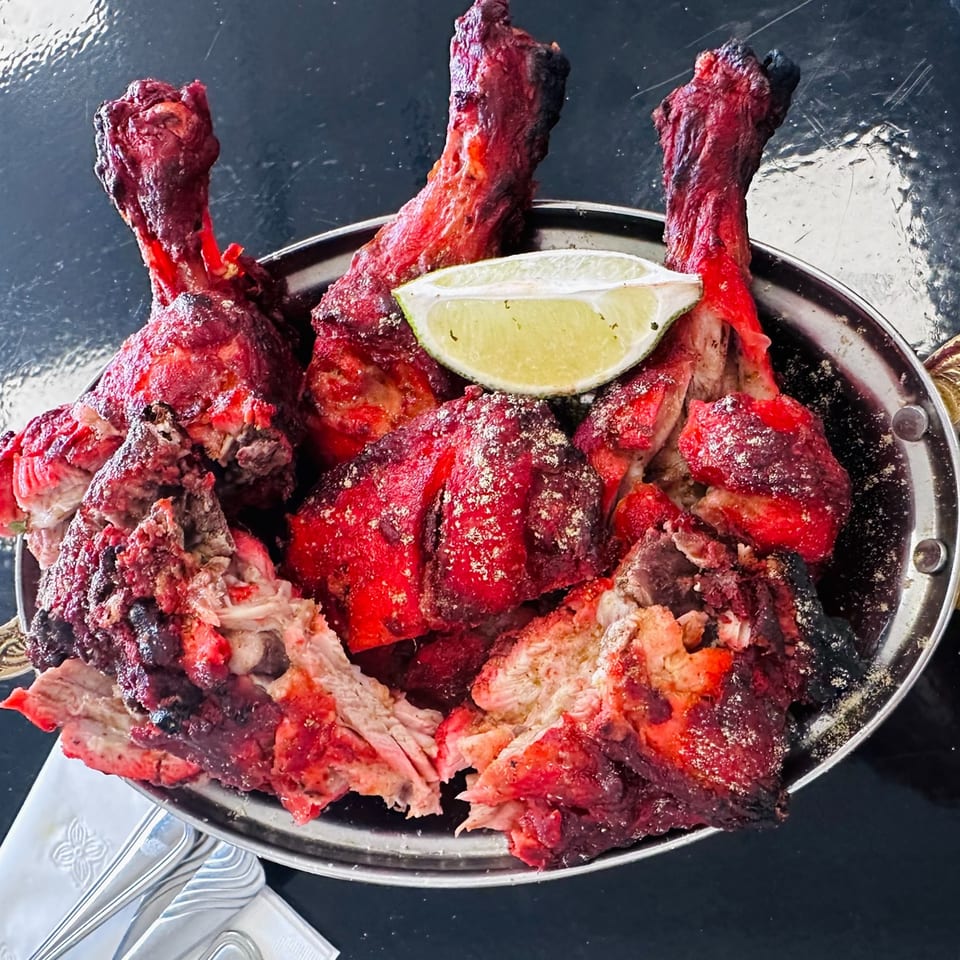 Zaika's vibrant red Tandoori chicken drumsticks and pieces, garnished with a fresh lime wedge.